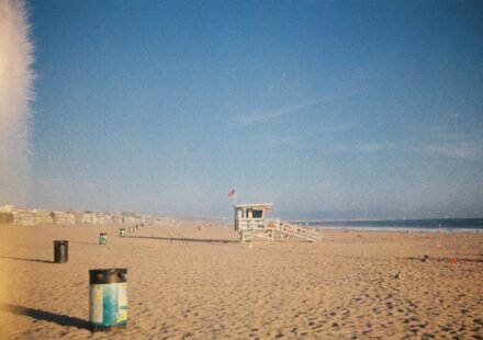 A wooden lifeguard tower on a sandy beach under a clear blue sky.