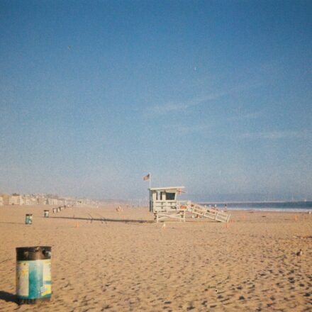 A wooden lifeguard tower on a sandy beach under a clear blue sky.