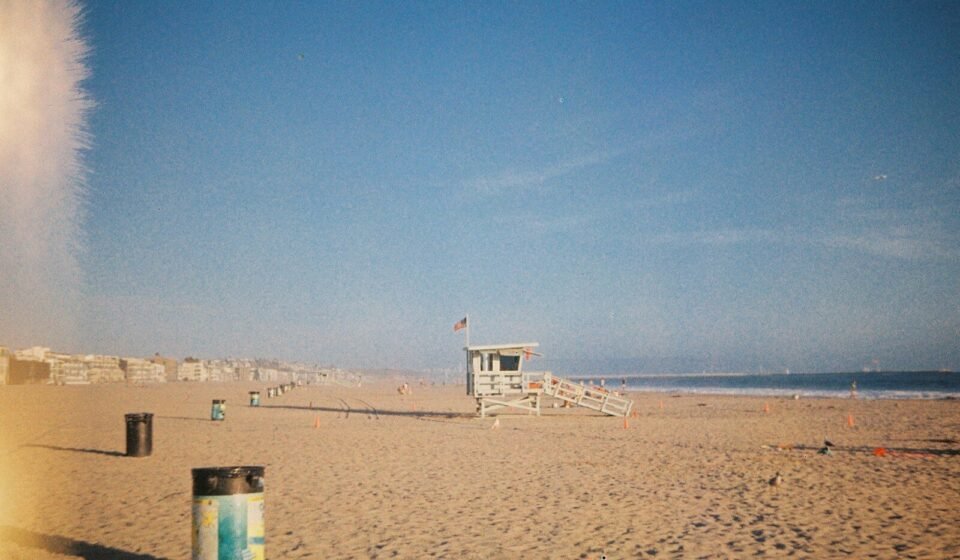 A wooden lifeguard tower on a sandy beach under a clear blue sky.